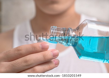 Hand of man Pouring Bottle Of Mouthwash Into Cap. Royalty-Free Stock Photo #1810201549