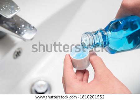 Hand of man Pouring Bottle Of Mouthwash Into Cap. Royalty-Free Stock Photo #1810201552