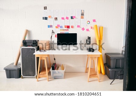 Workspace In Creative Studio With Desk And Computer In Front Of Wall With Fashion Designs