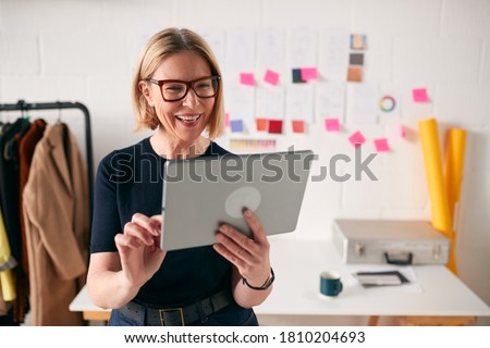 Mature Businesswoman Using Tablet Computer In Studio Of Start Up Fashion Business Royalty-Free Stock Photo #1810204693