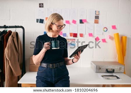 Mature Businesswoman Using Tablet Computer In Studio Of Start Up Fashion Business Royalty-Free Stock Photo #1810204696