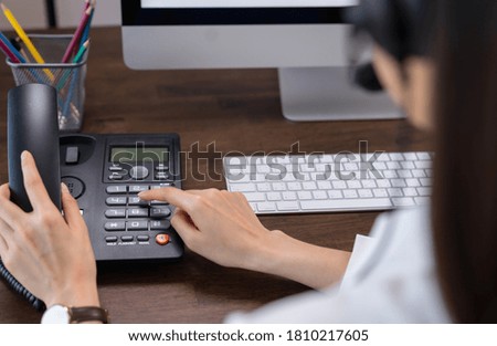 Woman hand holding the phone and working laptop on the office desk.