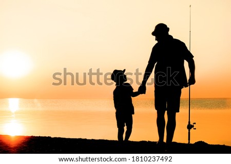 Happy father and child fishermen catch fish by the sea on nature silhouette travel