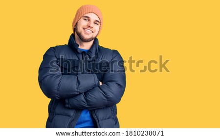 Young handsome man wearing winter clothes happy face smiling with crossed arms looking at the camera. positive person. 