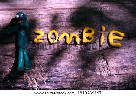 Zombie lettering on a dark background. Next to it is a plasticine zombie figurine.