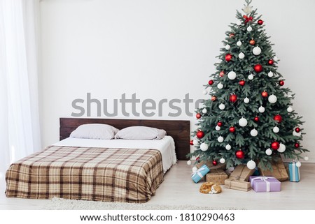 Christmas tree in the interior of the bedroom with a bed and pads for the new year