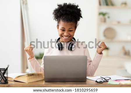 Little Winner. Excited Black Girl At Laptop Gesturing Yes Getting A-Grade During Webinar At Home. Online School Tests Concept Royalty-Free Stock Photo #1810295659
