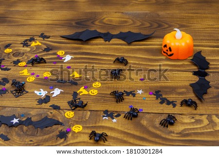 Halloween composition with jack-o-lantern, confetti, spiders and bats on wooden background
