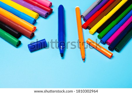 different types of colored markers and pencils on a blue background