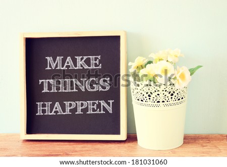 make things happen message written on a chalkboard and flowerpot decoration over wooden background