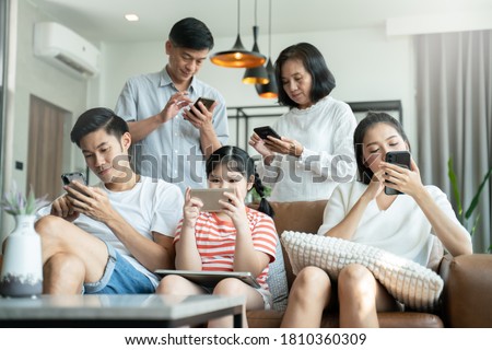 5G Technology for Families concept.Everyone sitting in sofa and using digital devices in living room.Big family grandmother grandfather and kids spending time together at home. Royalty-Free Stock Photo #1810360309
