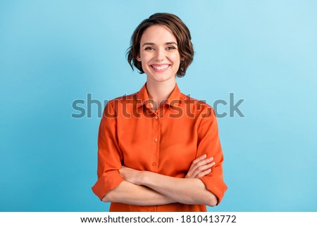Photo of attractive bossy lady bobbed hairdo arms crossed self-confident person worker friendly smile white teeth good mood wear orange office shirt isolated blue color background