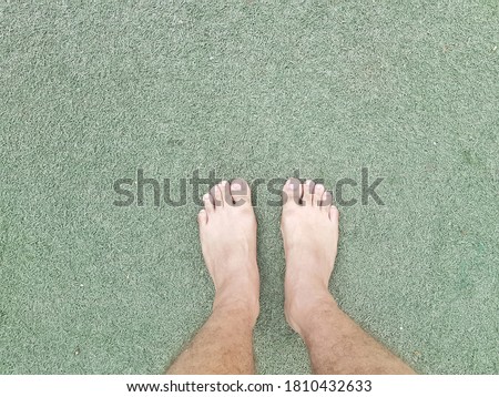 bare feet standing over fake grass
