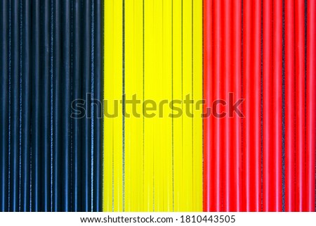 Top view of black, yellow and  red plastic drinking straws in a row. Colours of flag of Belgium.