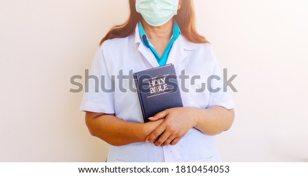 Doctor in uniform holding bible and praying in hospital room with hope.Coronavirus Covid-19.Church online in sunday service. Doctor with faith and praying to GOD.Religion during covid-19 crisis.