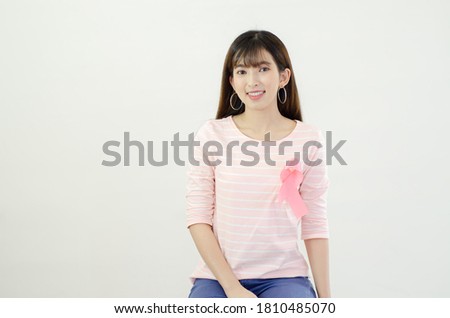 Pink ribbon affixed on an Asian woman's shirt.Do not focus on objects.World Breast Cancer Day Concept.