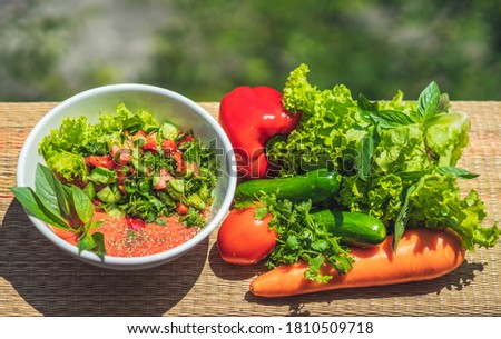 Raw vegan salad with green leaves mix vegetables in white bowl. Cooking recipe blended tomato carrot, parsley cilantro dill greenery cucumber, basil, bell pepper. Healthy food, vitamins for immunity