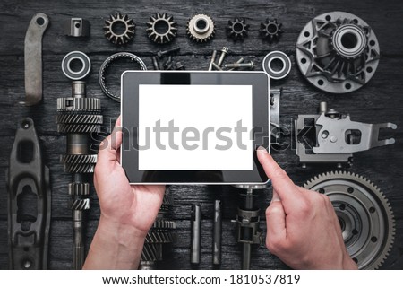 Car service worker is holding a blank screen digital tablet above spare parts background. Car spare parts order online concept. Royalty-Free Stock Photo #1810537819