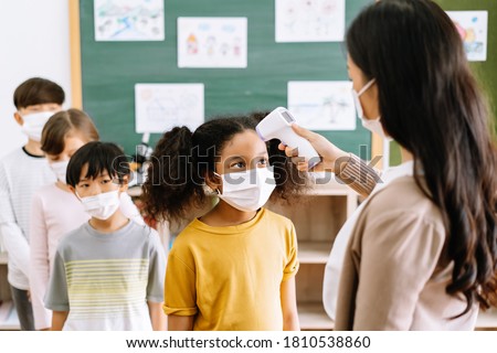 Group of Elementary School Pupils with face mask stood in line let the teacher check, scan thermometer temperature for fever against the spread virus in classroom after covid-19 quarantine,lockdown. Royalty-Free Stock Photo #1810538860