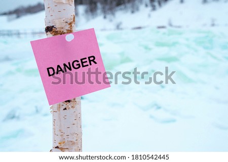the sign with the inscription is dangerously attached to a birch stick, the background is broken ice. in winter by the reservoir