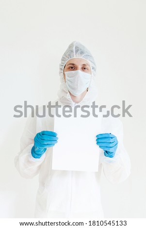 a man in a protective suit, gloves and face mask holds a sign in his hands. Isolated on a white background