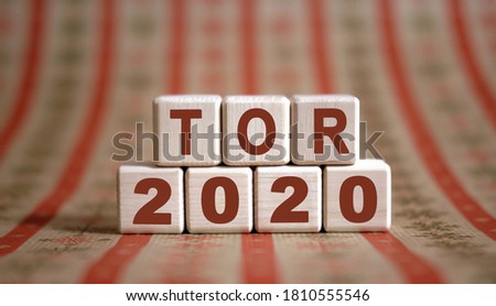 TOR 2020 text on wooden cubes on a monochrome background with reflection.