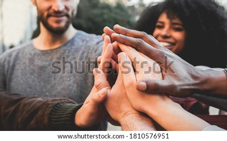 Young happy people stacking hands outdoor - Multiracial students celebrating together - Focus on hands Royalty-Free Stock Photo #1810576951