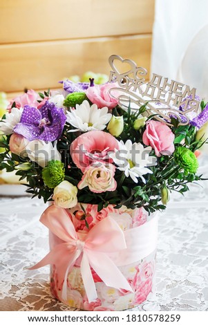 Festive bouquet of various flowers in a round gift box. Flowers for birthday. A bouquet of flowers on the table. The inscription "Happy Birthday" in Russian.