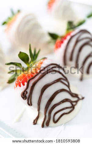 White and dark chocolate dipped strawberries on a white cake stand.