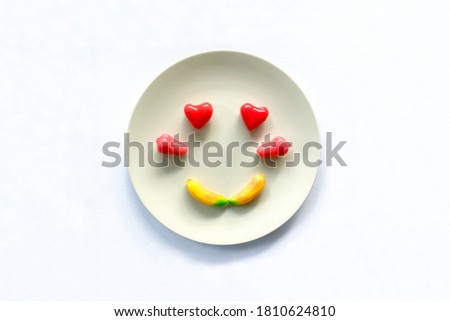 Fruit Shaped Mung Beans or Kanom Look Choup is Thai dessert made from mung beans and sugar. Hands craft shaped fruits colorful decorations in love emotion smile face on plate in white background