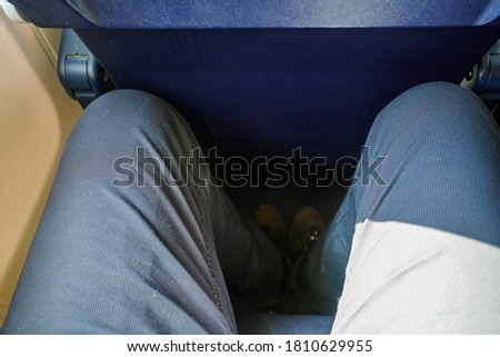 Looking down at narrow leg space in low cost airline seat, knees touching back rest at front Royalty-Free Stock Photo #1810629955