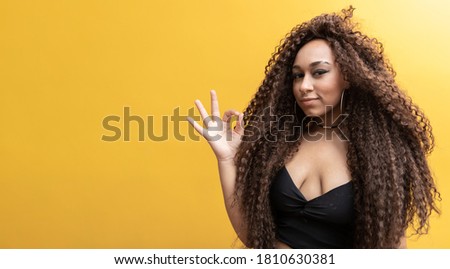 afro woman on yellow background making ok sign with her hand