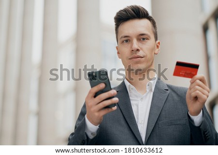portrait of a man of European appearance. holds a phone and a Bank card, wants to pay for purchases in an online store with home delivery