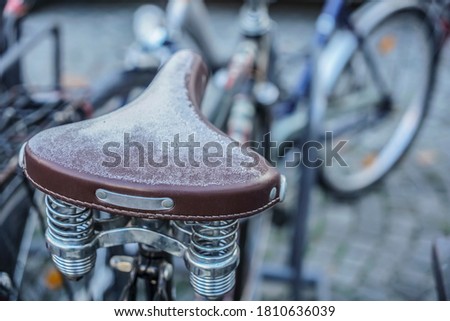 Saddle frostbite during a cold day, old seat with springs. Saddle of a bicycle covered with a layer of snow.