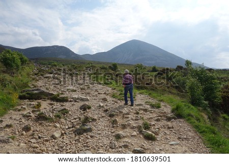 Man walkes uphill on a sandy street . Rocky hills with sand rocks . Lonely hiker hiking a stone way hill up .