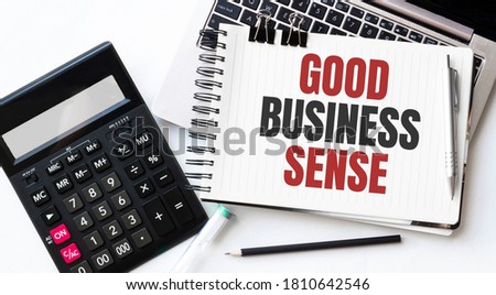 Keyboard of laptop, calcualtor, pencil and notepad with text GOOD BUSINESS SENSE on the white background