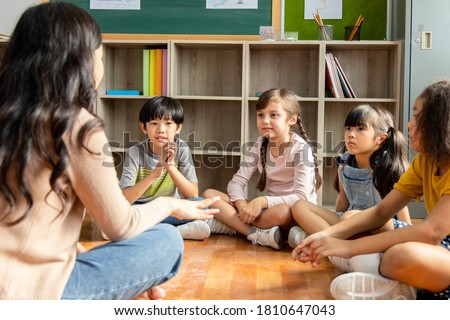 Diversity Elementary school students who sit on the classroom floor listen to Asian female teachers tell stories. Concept of education and learning Royalty-Free Stock Photo #1810647043