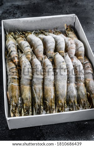 Package of frozen tiger prawns, shrimps. Black background. Top view