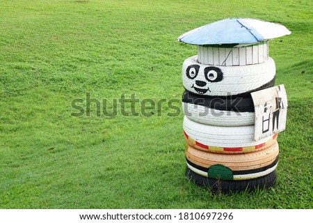 Funny trash bin made from old tires. Recycled tires trash bin in garden. Do It Yourself (D.I.Y) ideas for outdoor and garden decoration. Selective focus, blurred green grass background with copy space