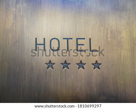 HOTEL  signboard with  four 4 stars metallic plate next to entrance door. 4 four golden stars. empty copy space for inscription.