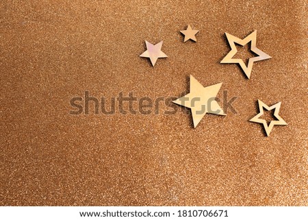 Rose gold stars and glitter on light brown background. Holiday party decoration. New year celebration.