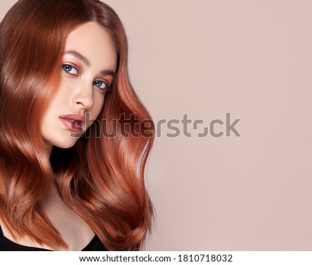 Beauty redhead girl with long  and   shiny wavy red hair .  Beautiful   woman model with curly hairstyle .
