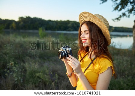 Woman photographer with a camera in her hands smile red lips hat nature landscape