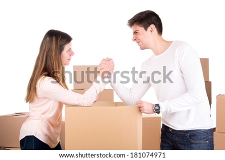 Young couple arm wrestling over boxes moving into new home apartment 