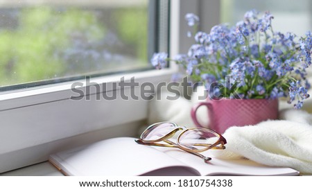 white warm plaid blanket and notebook, glasses on wooden rustic bench. Photo toned, selective focus. Cozy home still life: spring flowers with warm plaid on windowsill