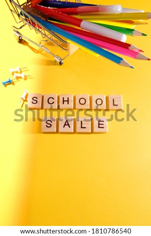 School sale with trendy shadow and different supplies on yellow background. Lettering school sale are made out of blocks