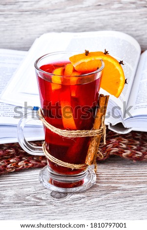 Mulled wine Hot christmas drink with spices on wooden background. Orange slice, cinnamon sticks, books and sweater. Christmas morning. Holiday atmosphere, Rustic style. The idea for creating greeting