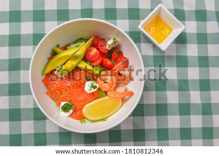 Fresh salad with seafoods, tomato and herbs. Red salmon, small shrimps, avocado, cherry tomatoes. Delicious concept for dinner.