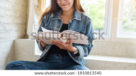 Closeup image of a beautiful asian woman sitting and reading book at home