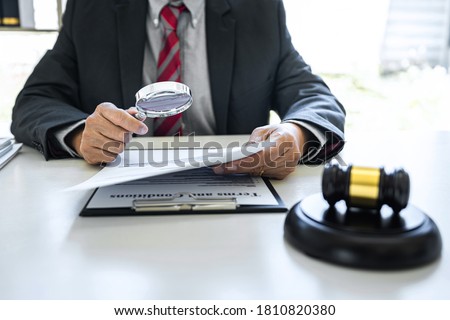 Male lawyer or judge working with contract papers, Law books and wooden gavel on table in courtroom, Justice lawyers at law firm, Law and Legal services concept. Royalty-Free Stock Photo #1810820380